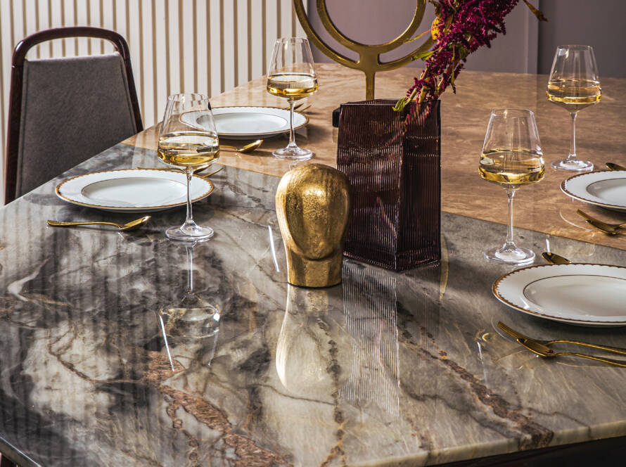 Marble-top dining table set for dinner with brass accents